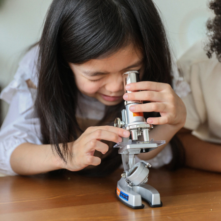 Petit fille en train d'observer quelque chose au microscope