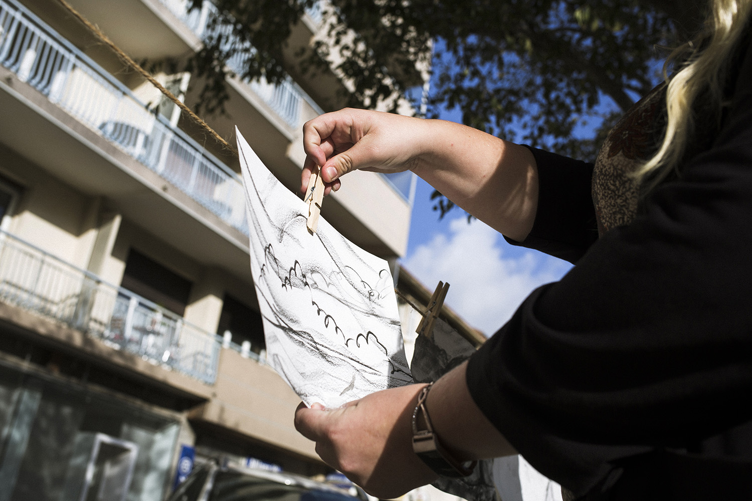 Une personne accroche un dessin pendant la Grande Lessive 2019