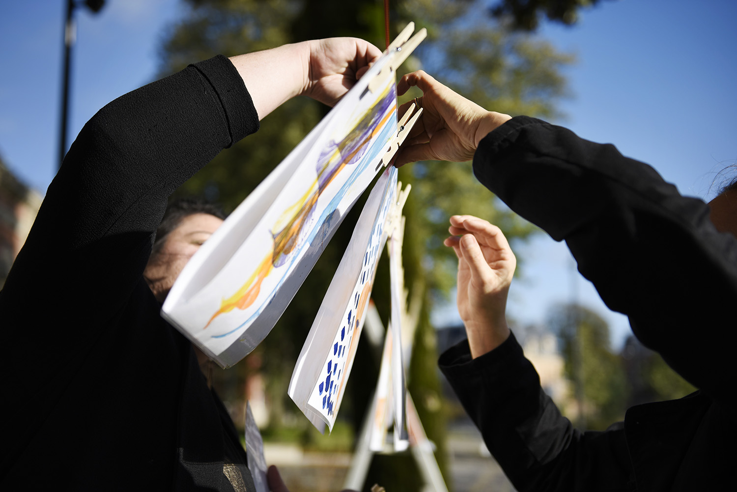 Deux personnes accrochent un dessin pendant la Grande Lessive 2019