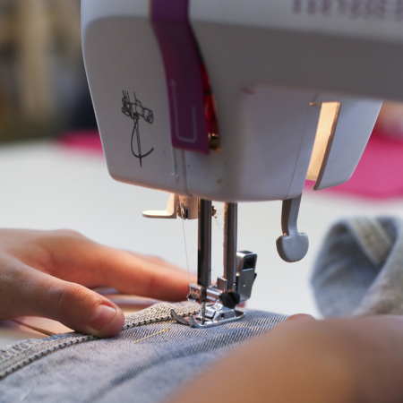 Adhérent en train de coudre à la machine pendant un cours de couture de l'ECLA