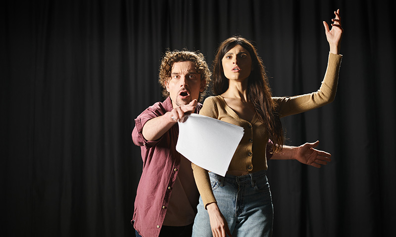 Deux élèves d'un cours de prise de parole ou de théâtre lisent un texte sur scène
